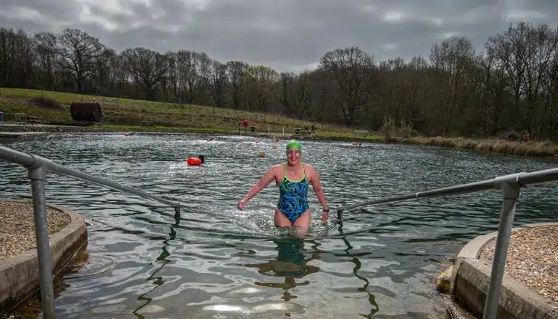 A happy woman finishing her wild swimming session at Andark Lake in Hampshire