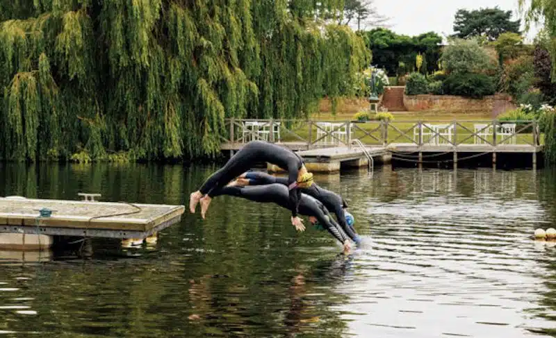 Two swimmers in wetsuits dive into Fritton Lake in Norfolk
