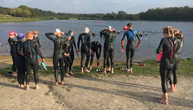 Swimmers in wetsuits and swimming caps entering the lake at Hetton Lyons in County Durham