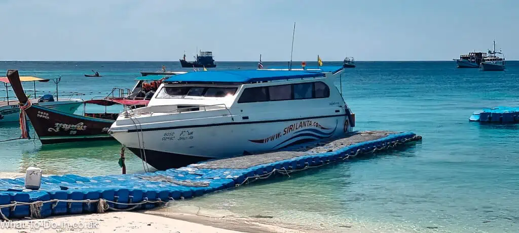 A speedboat moored to the floating, blue jetty on Pattaya Beach, Koh Lipe, Thailand