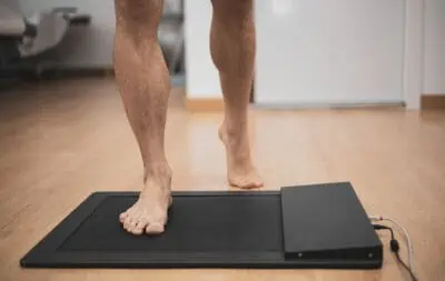 a man in a medical office specialized in posurology with his feet on a platform to analyze the pressure exerted and the biomechanical study of foot drop